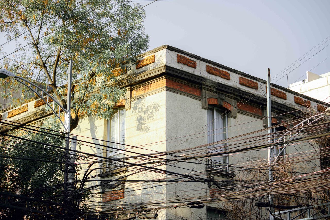 Historic building facade with dense overhead utility wires and surrounding trees.