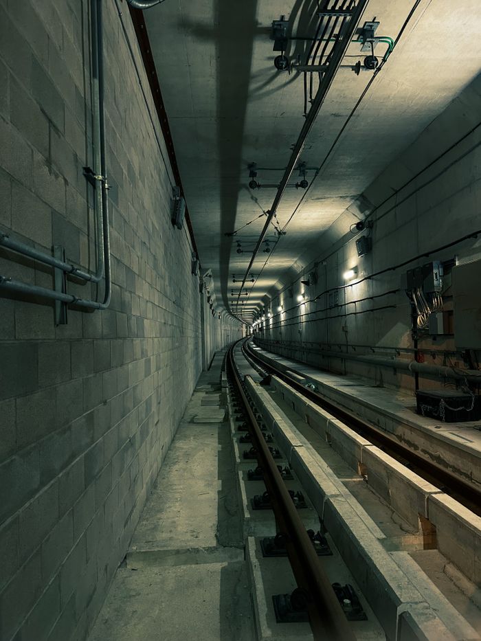 about-03 Atmospheric underground metro railway tunnel with visible rails and concrete walls, showcasing urban infrastructure.